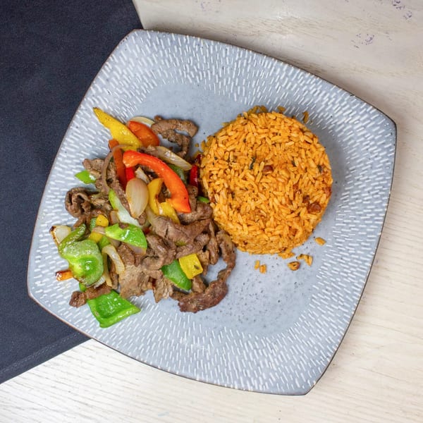 Stir-fried beef with colorful bell peppers and onions, served alongside a mound of orange rice.