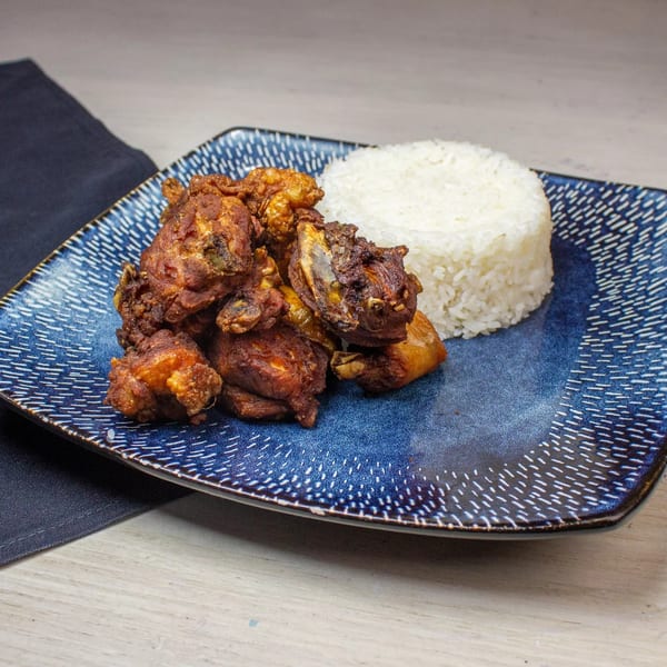 Crispy fried chicken pieces and a mound of white rice on a blue patterned plate.